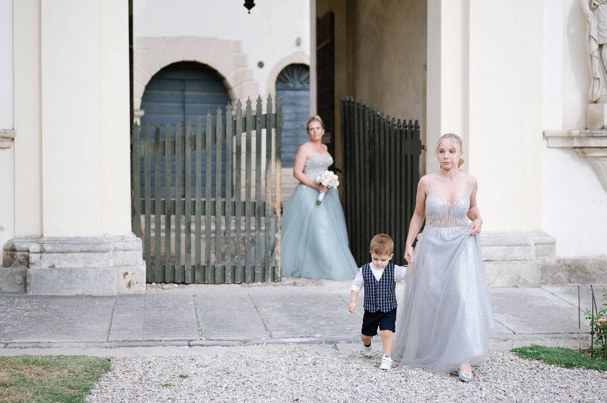 A gravel pathway leads to an elegant white villa with formal gardens and decorative iron gates.