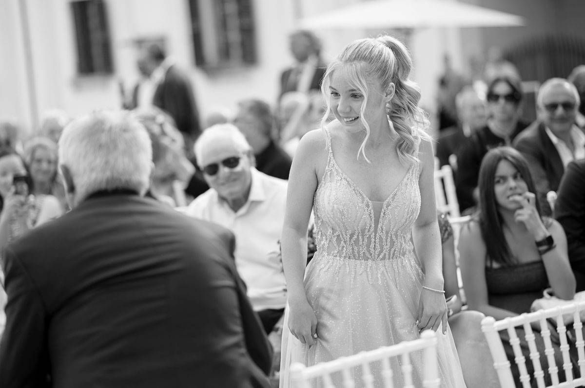 Black and white photograph capturing a joyful moment during an outdoor wedding ceremony.