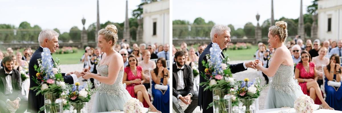 A couple celebrates during an outdoor wedding ceremony surrounded by guests and floral decorations.