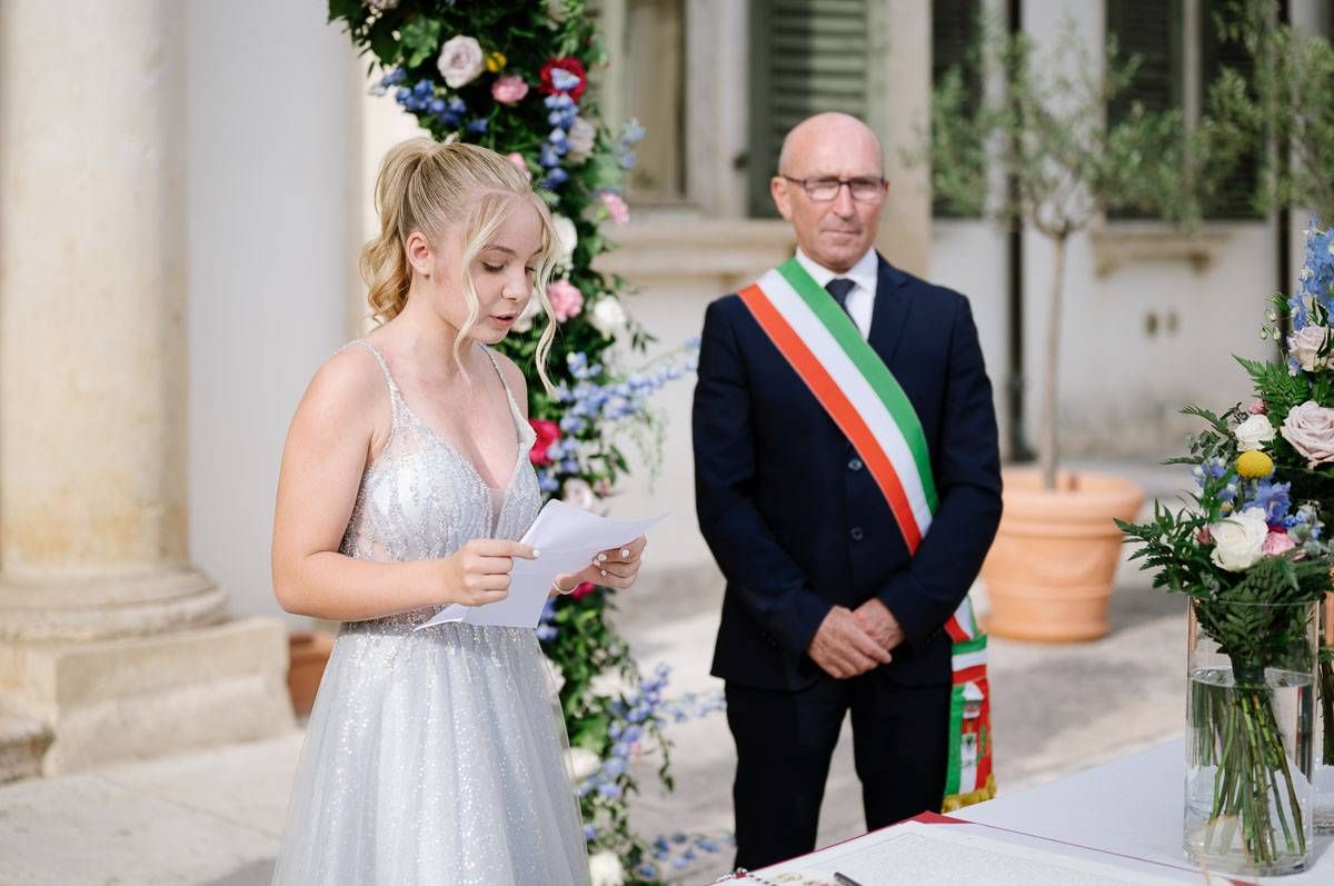 A wedding ceremony at an elegant venue with floral decorations and columns.