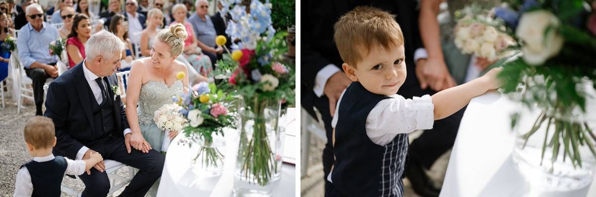 Small child in formal attire sits among guests during an outdoor wedding ceremony.