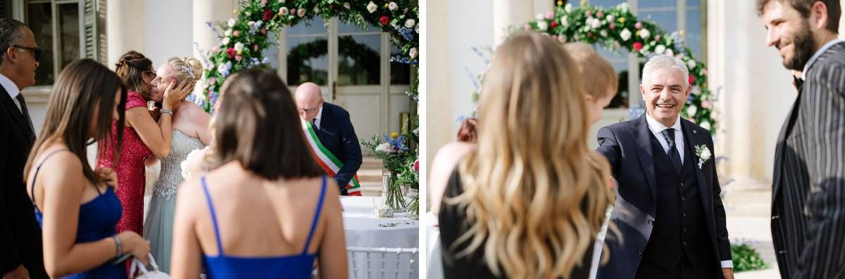 Wedding guests mingling under decorative floral arch at elegant outdoor ceremony.