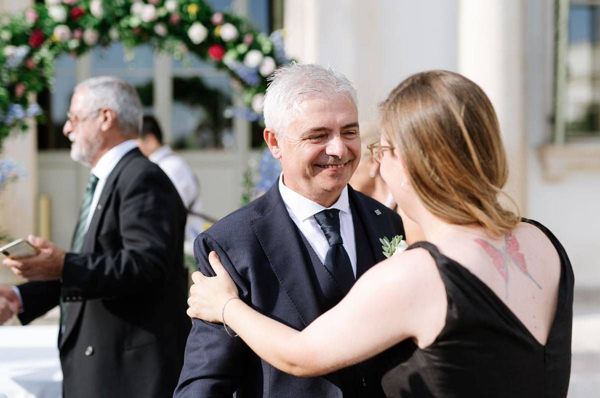Emotional exchange between guests during outdoor wedding celebration with floral decorations.