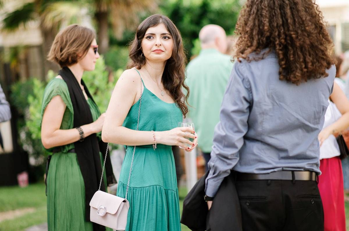 Wedding guests in colorful dresses socializing at outdoor reception.