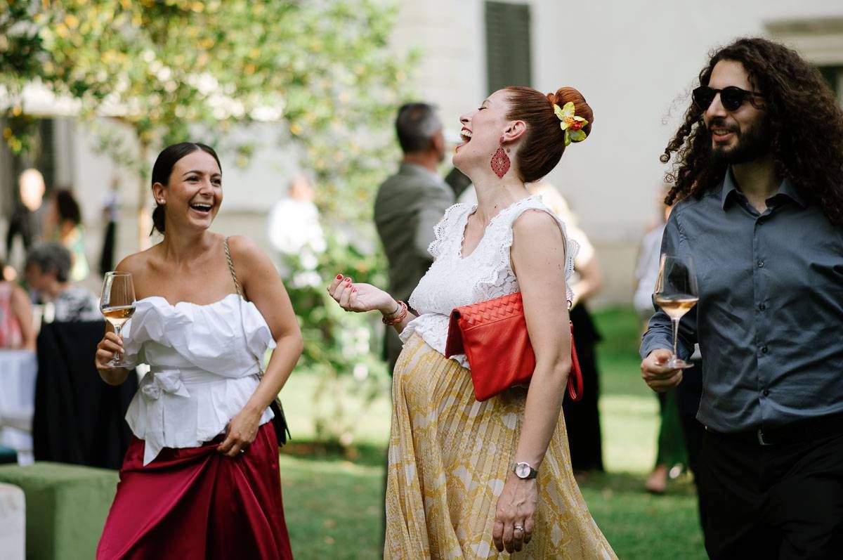 Group of guests enjoying drinks and laughing together at an outdoor garden party.