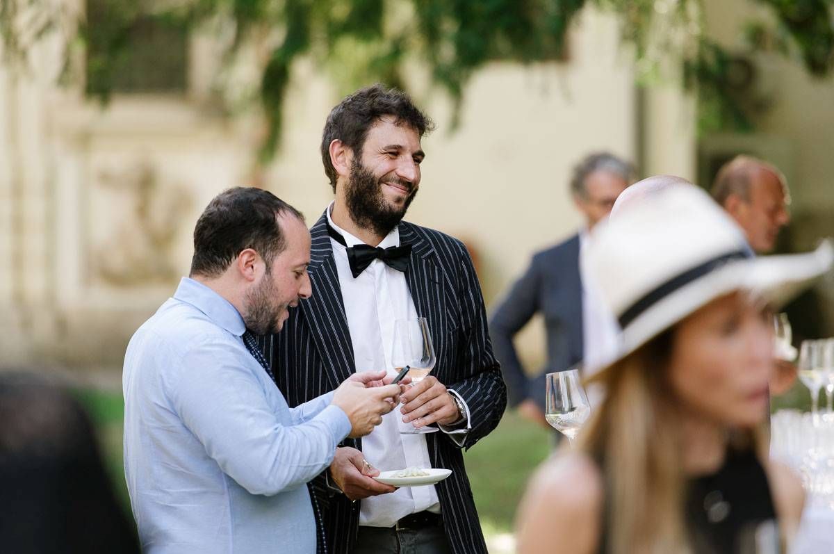 Guests in formal attire conversing at an outdoor event.
