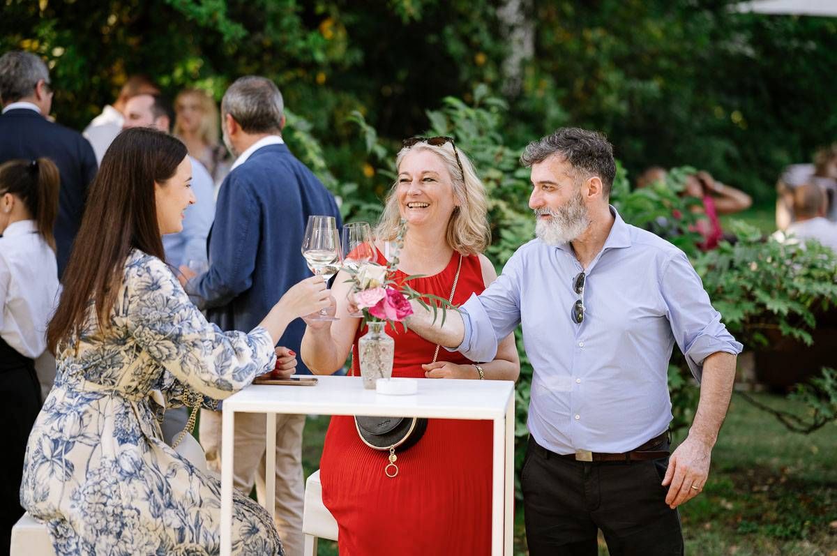 Group of guests socializing and raising wine glasses at outdoor garden party.