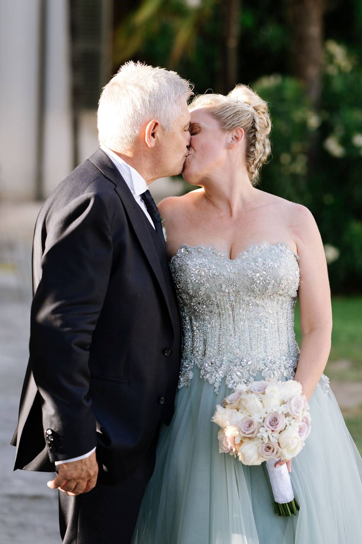Couple sharing romantic moment in formal attire with light blue gown and black suit.
