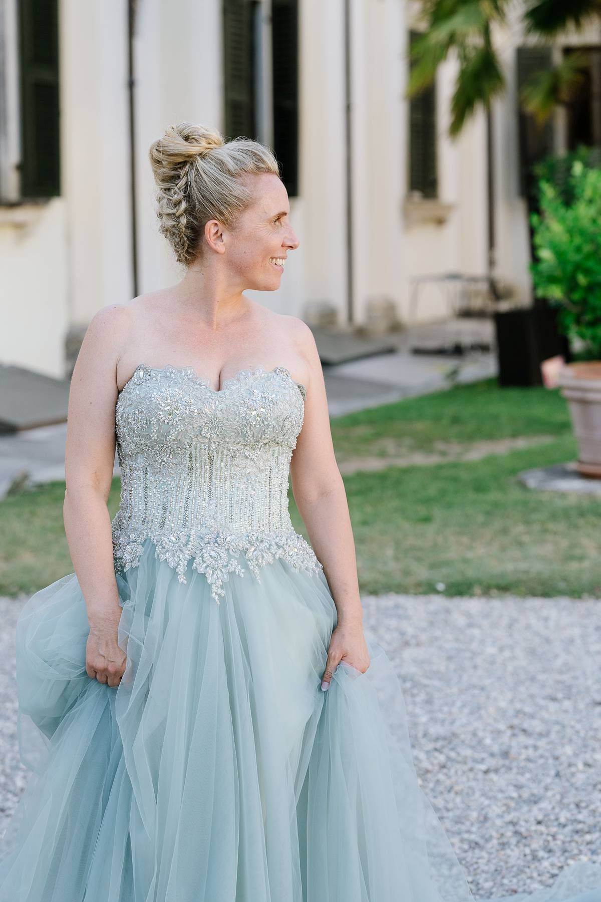 A pale blue ballgown with intricate beaded bodice and flowing tulle skirt photographed in an outdoor garden setting.