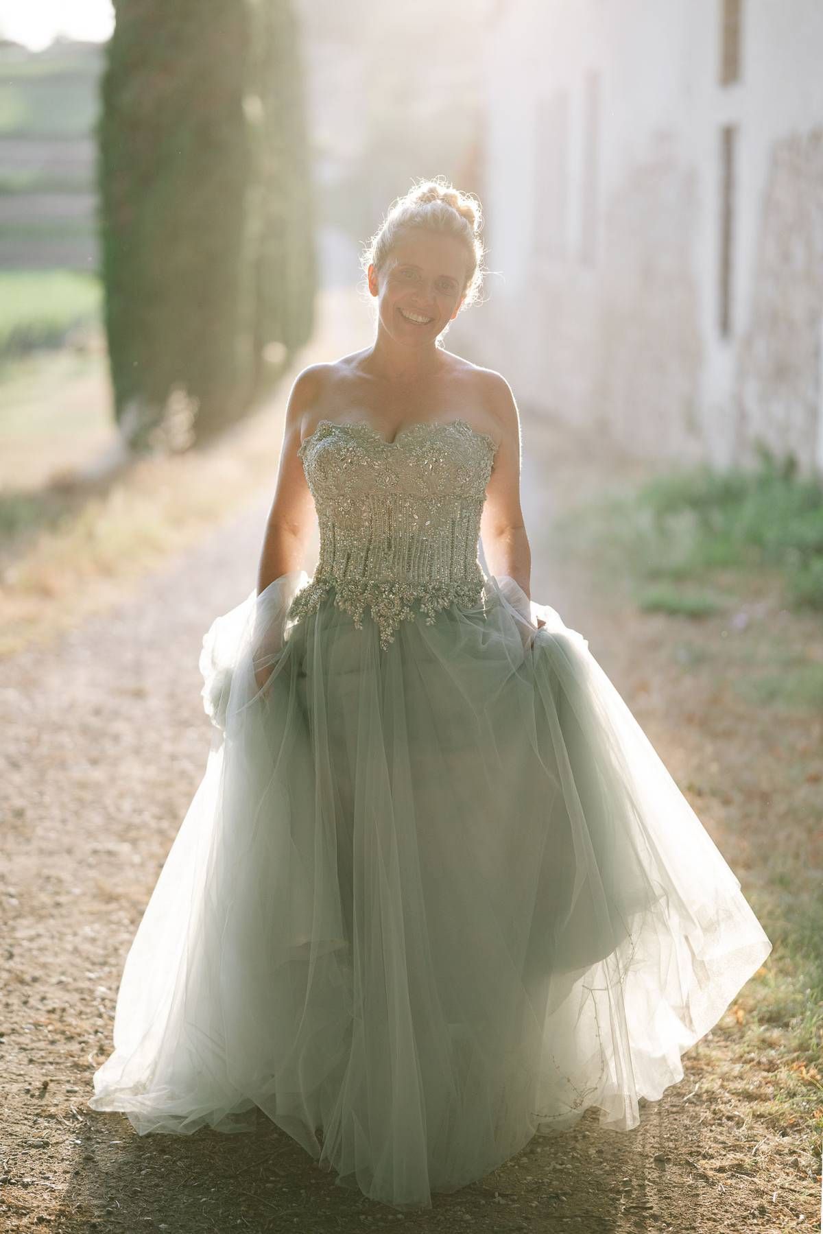 A joyful bridal moment captured in soft sunlight along a garden path.