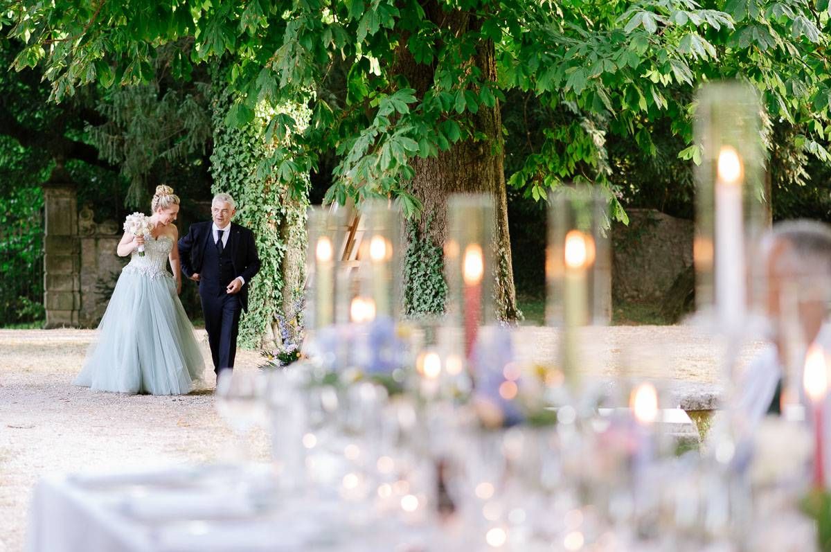Romantic outdoor wedding reception with candlelit table settings and lush greenery.