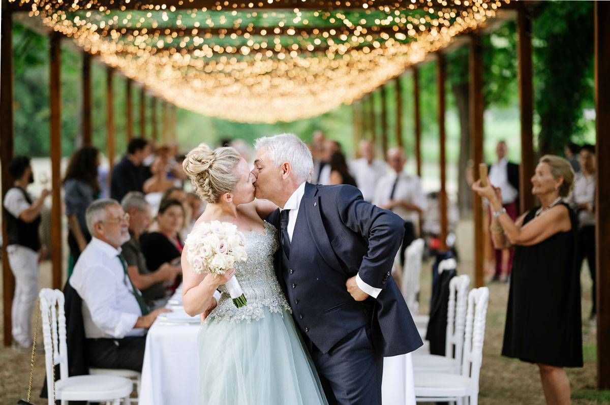 Wedding celebration under twinkling lights with guests watching the ceremony.