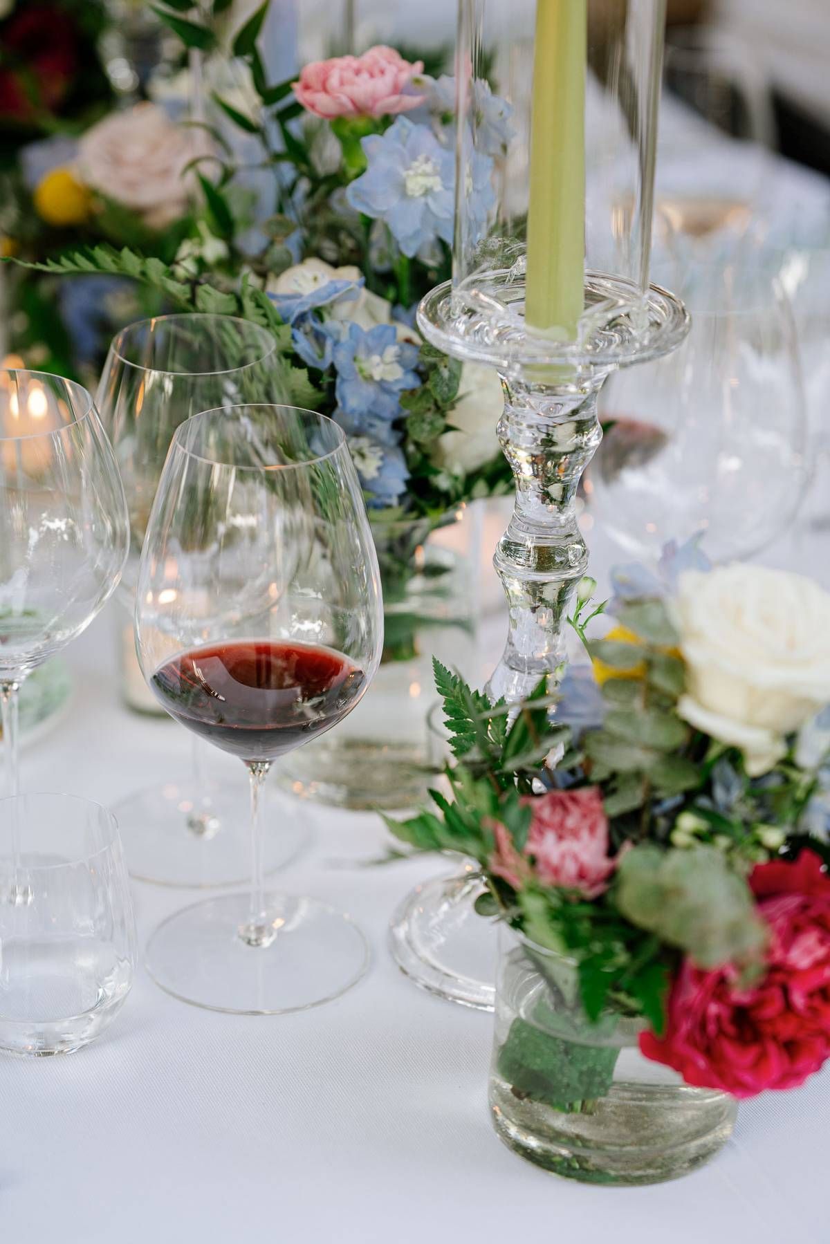 Romantic table setting with wine glasses, crystal candleholders and colorful flower arrangements.