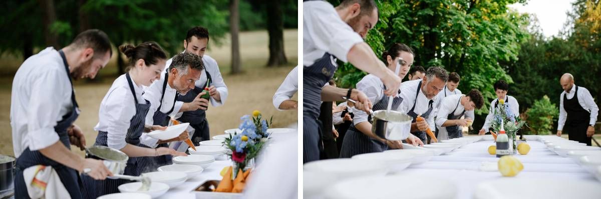 Restaurant staff in white shirts prepare dishes at an outdoor catering service table.