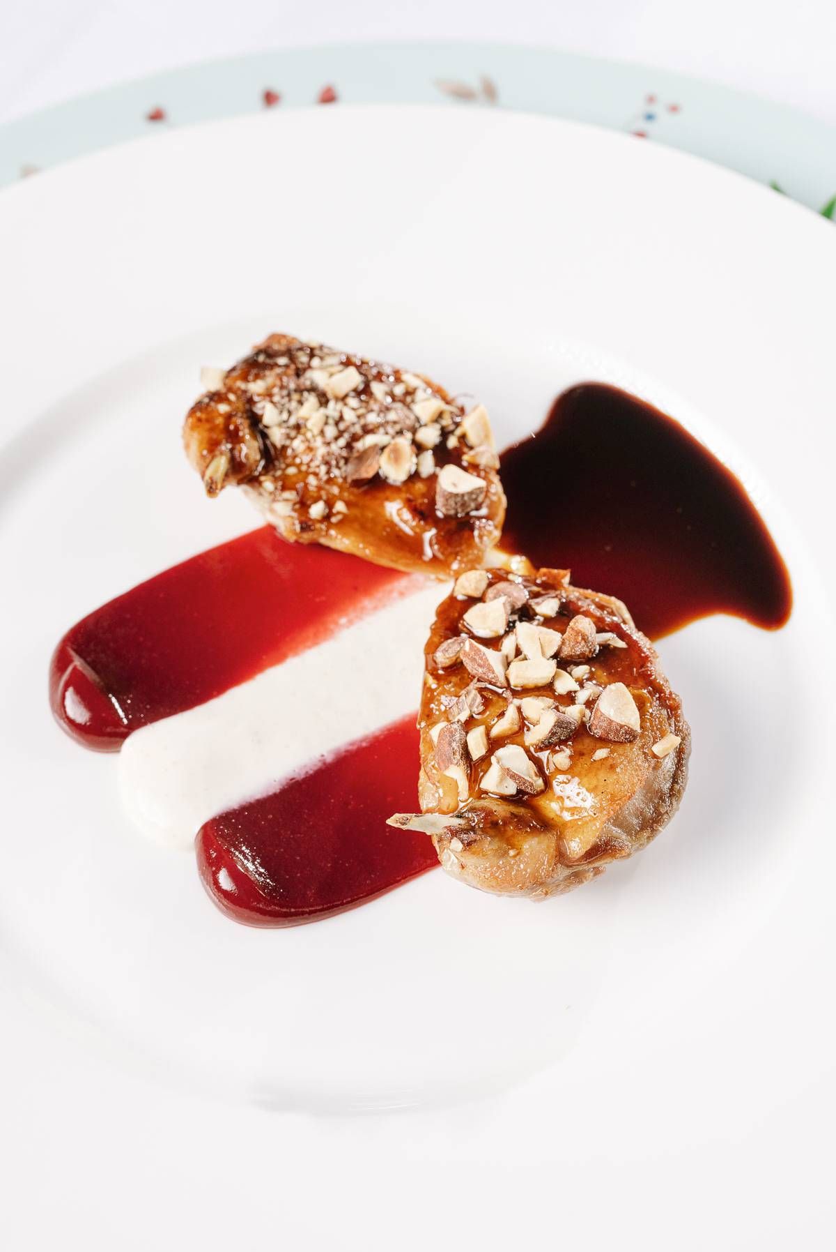 Gourmet dessert plate featuring pastry with nuts and red wine reduction sauce.