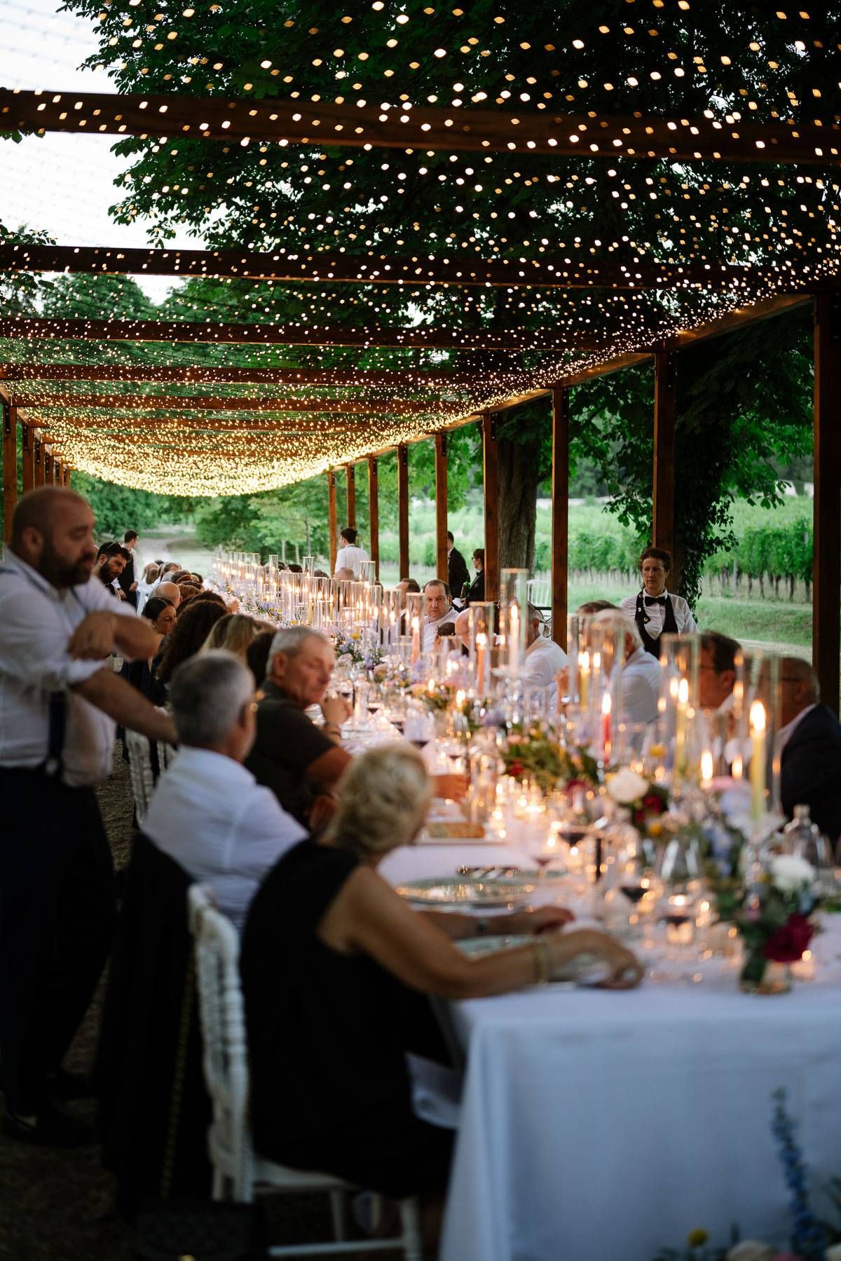 Outdoor wedding reception under twinkling string lights with elegantly set dining tables.