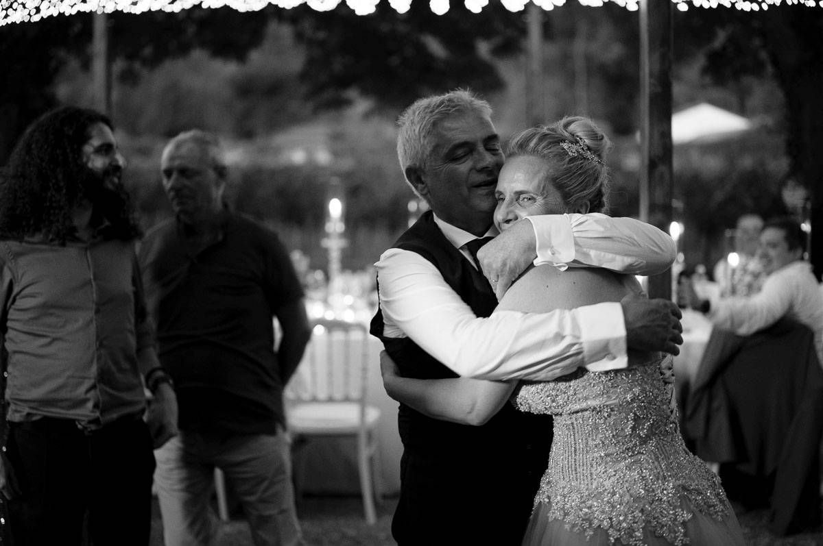 Couples dancing together at an evening outdoor celebration with string lights.