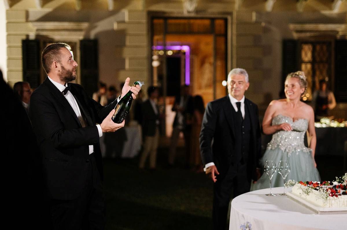 Wedding guest gives heartfelt toast while couple listens at outdoor reception.