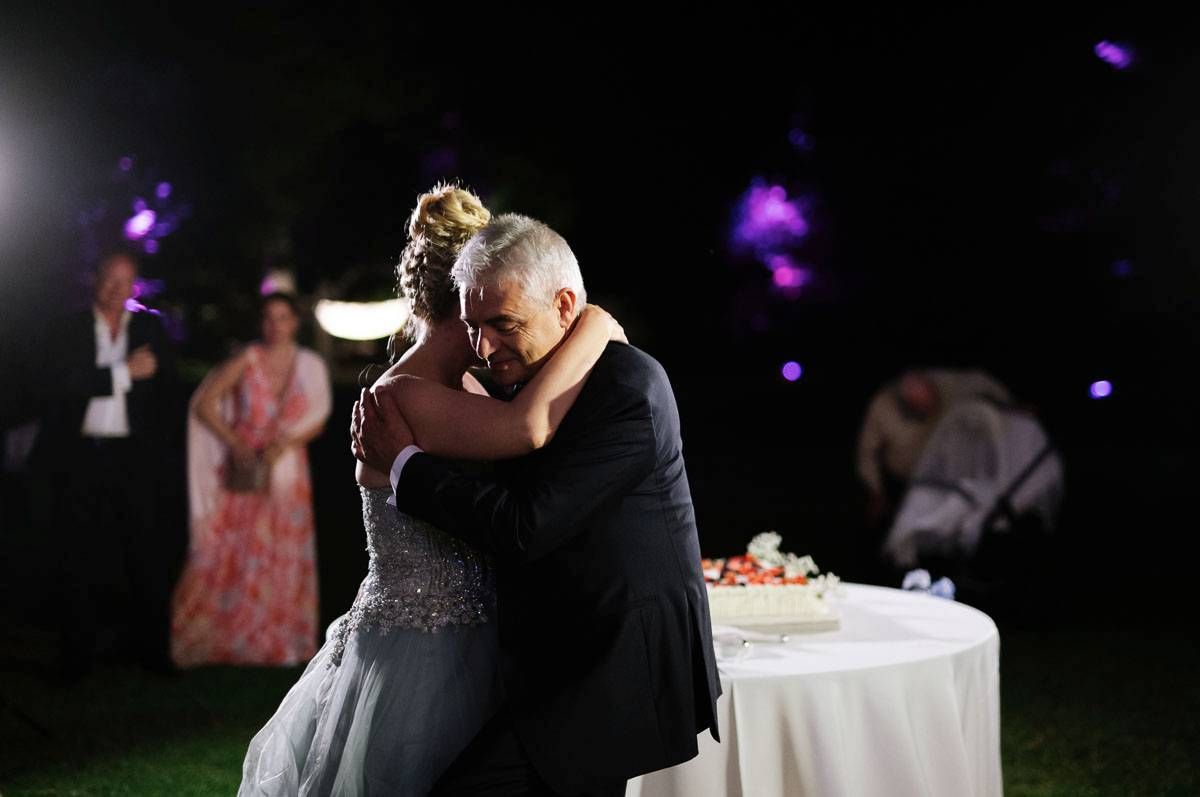 Couple shares romantic dance moment during outdoor nighttime wedding reception.