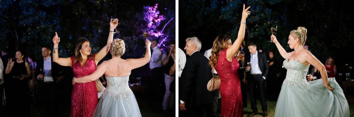 Guests dance and celebrate joyfully at an outdoor evening wedding reception with purple lighting.