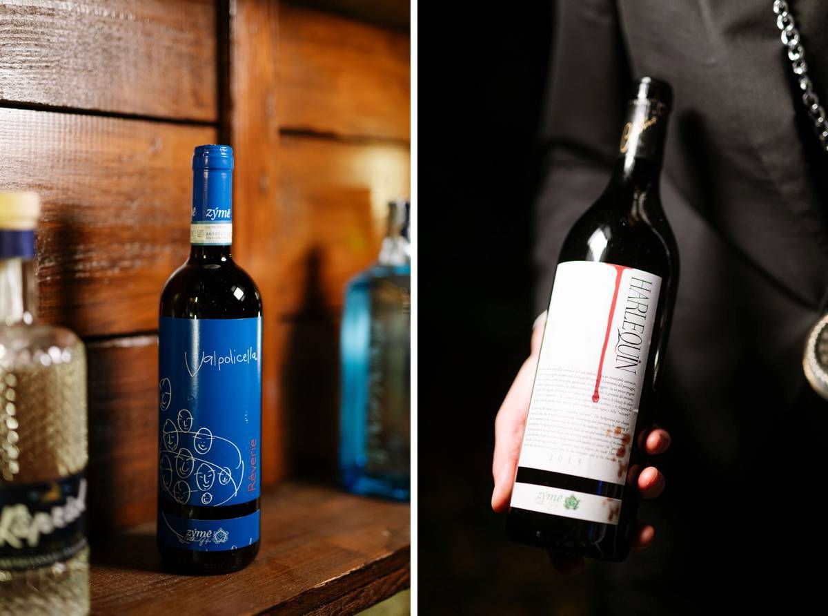 Wedding wine bottles displayed at reception, one blue decorated bottle and one being held.