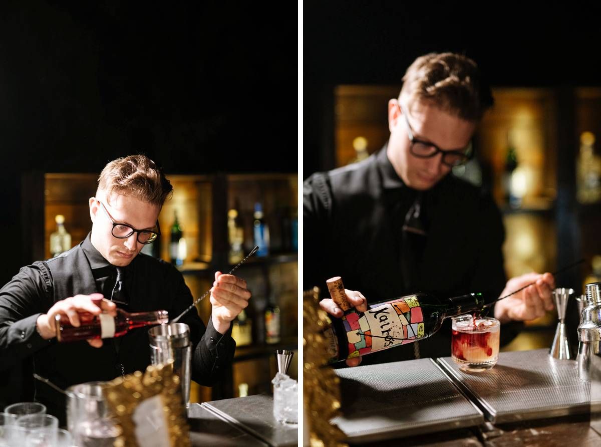 Bartender crafting cocktails in a dimly lit bar setting.
