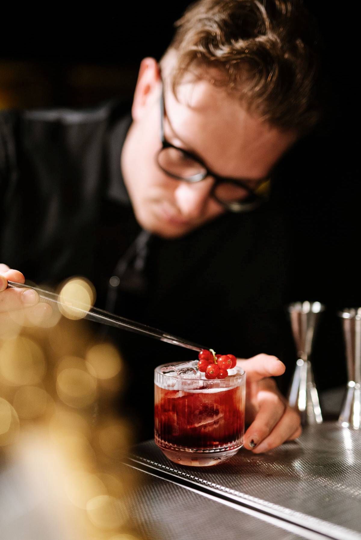 Artisanal cocktail being garnished with fresh berries at an upscale bar.
