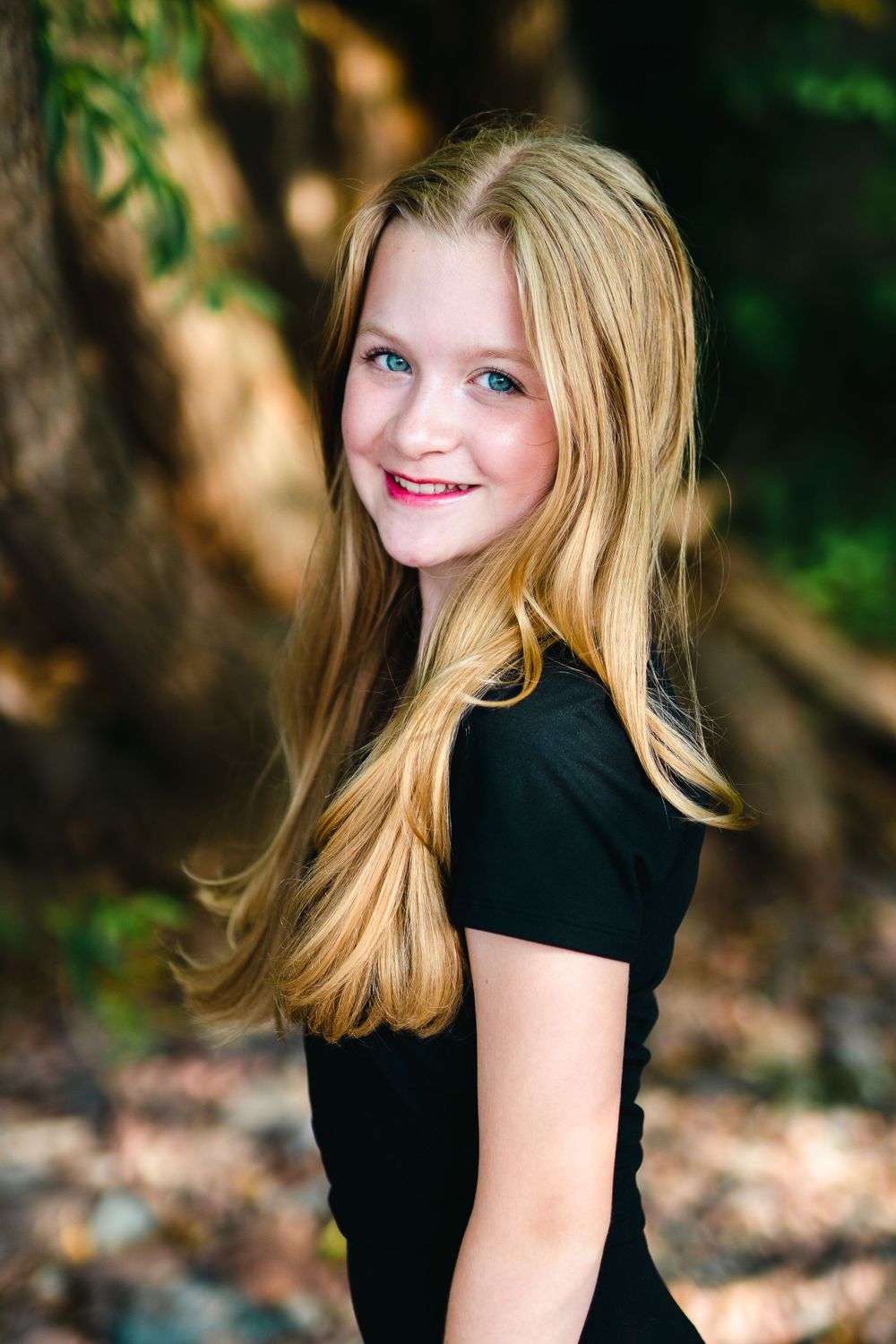 Portrait of person in black top with long blonde hair against natural background.