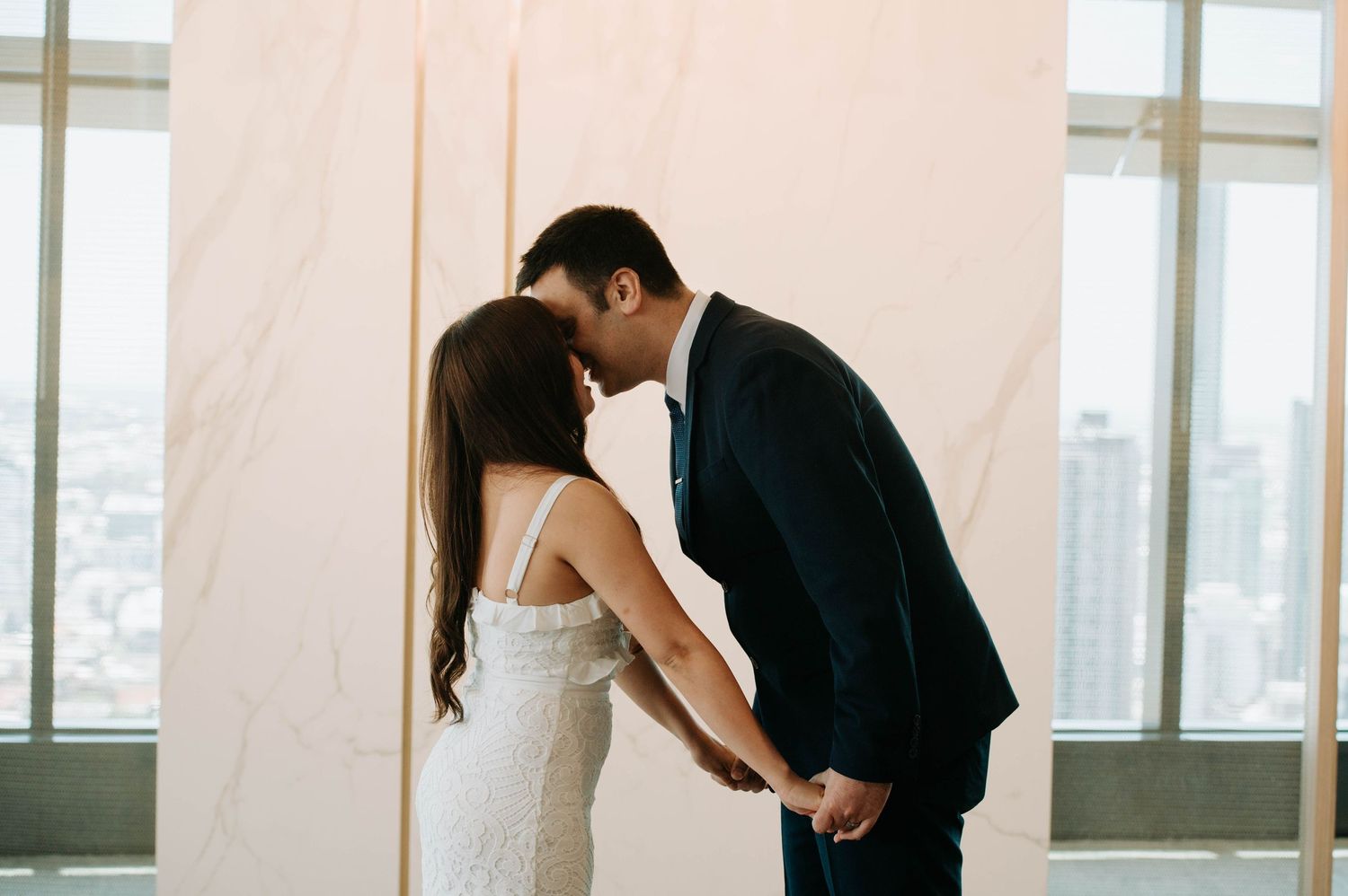 Romantic silhouette of newlyweds sharing an intimate moment against bright windows.
