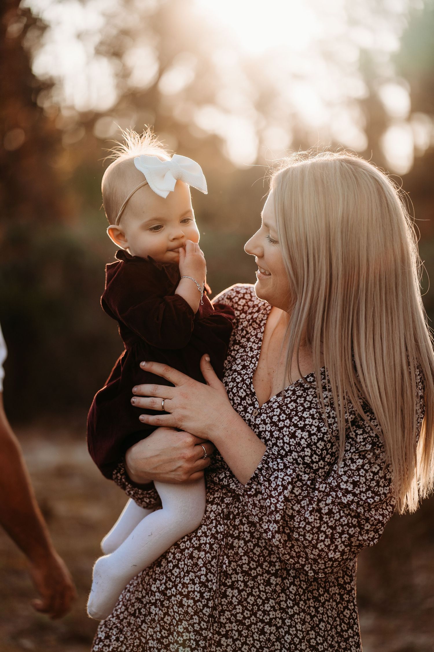 Mother and baby sharing tender moments at sunset in warm golden light.