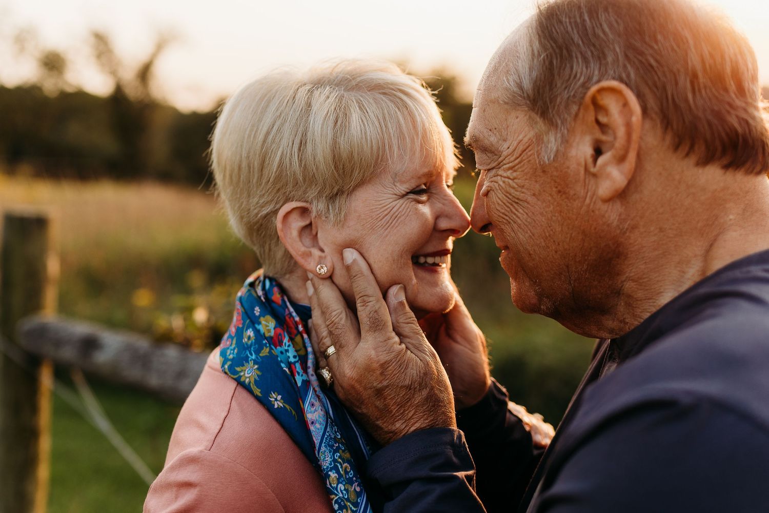 Tender moment shared between elderly couple in warm sunset light.