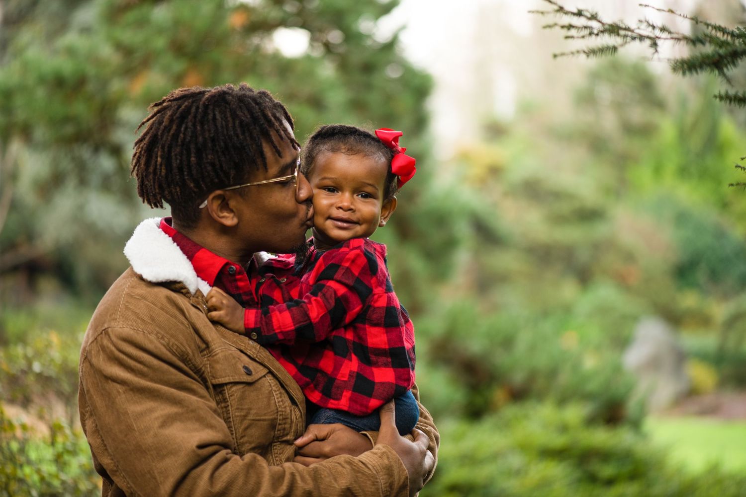 A heartwarming outdoor portrait in a lush garden setting with plaid clothing details.