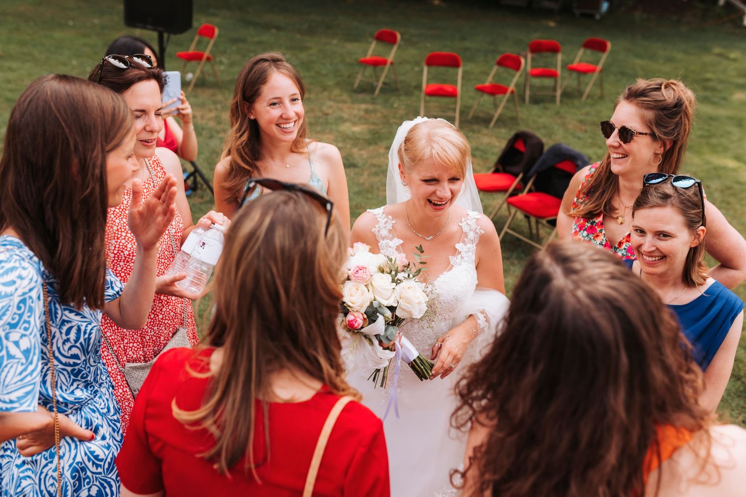 A joyful wedding gathering with guests in colorful attire celebrating outdoors.