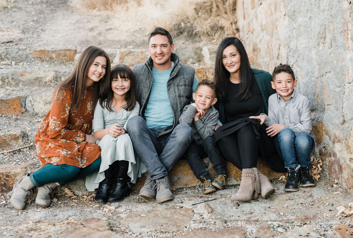 Family of 6 sitting on a stone stairway in the city