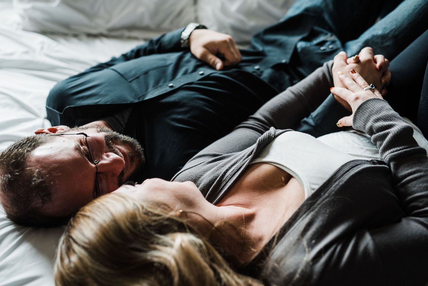 Man and Woman laying on a bed smiling at each other