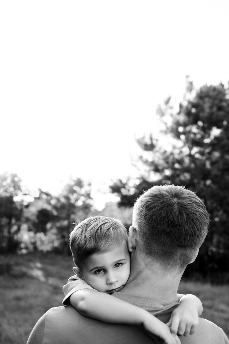 Black and white image of dad holding soon to be big brother on his shoulder.