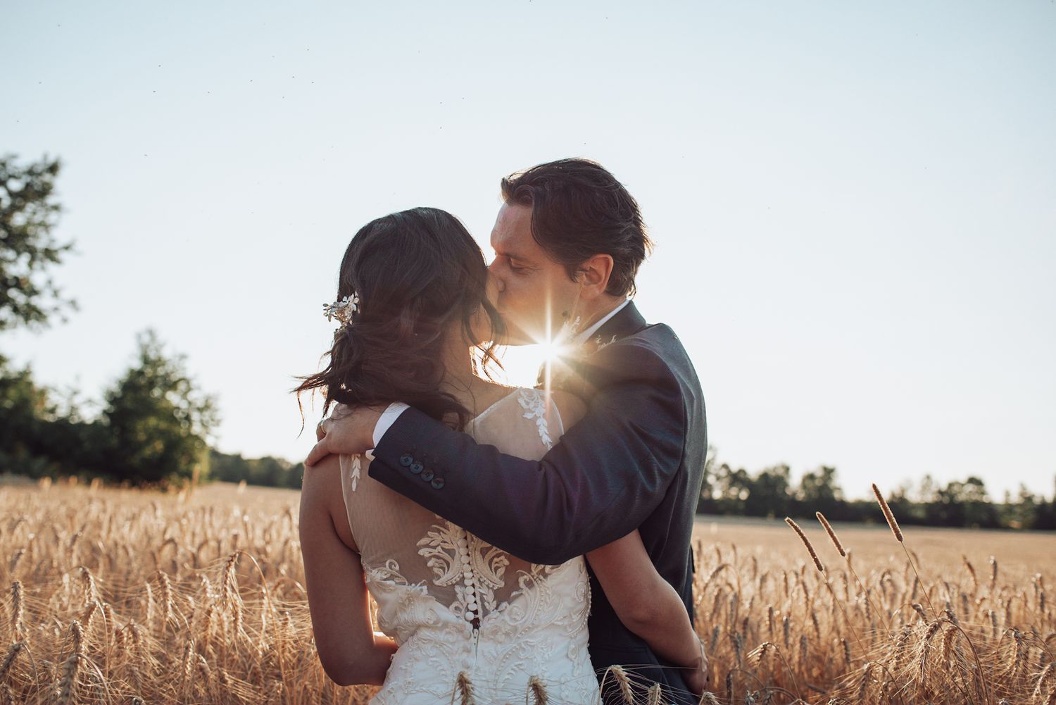 Romantic couple embracing in golden wheat field at sunset.