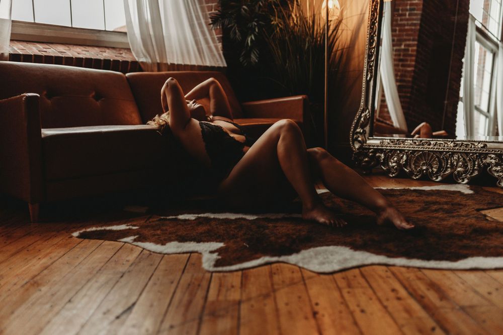 Intimate portrait in natural window light on hardwood floor with brown leather couch.