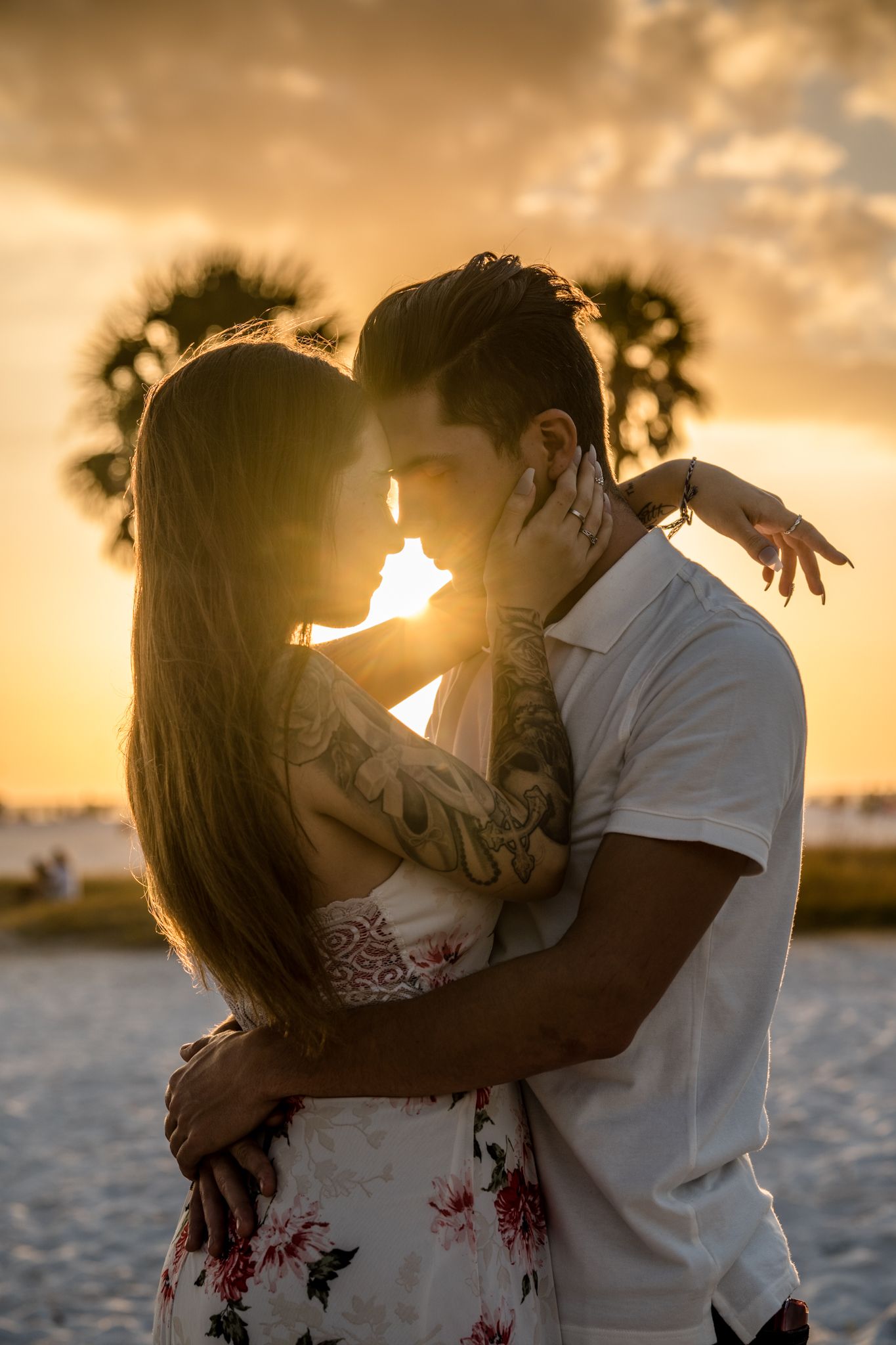 A romantic couple embraces on the beach during golden hour sunset.