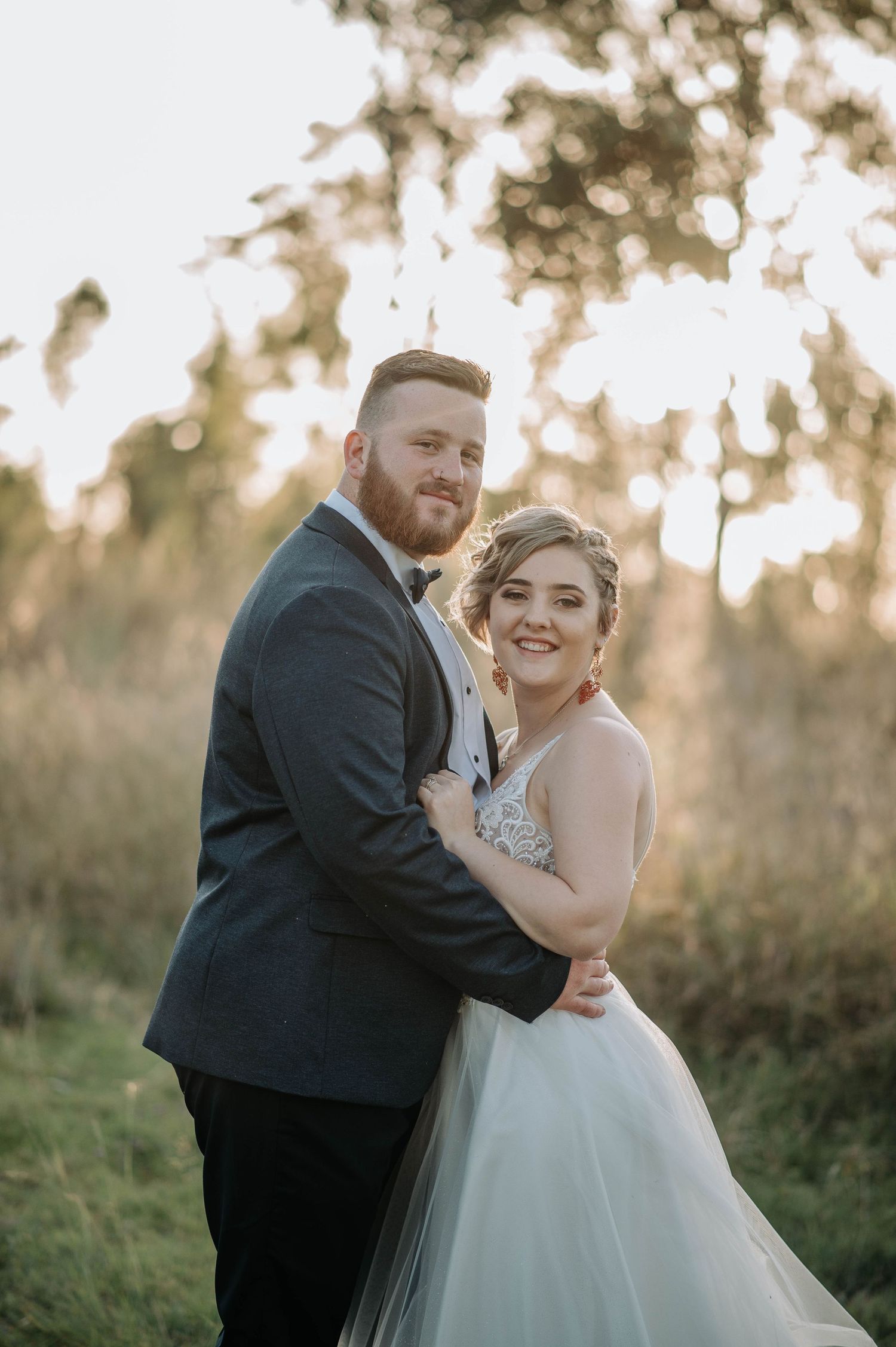 Joyful wedding portrait with natural backlit sunset in outdoor setting.