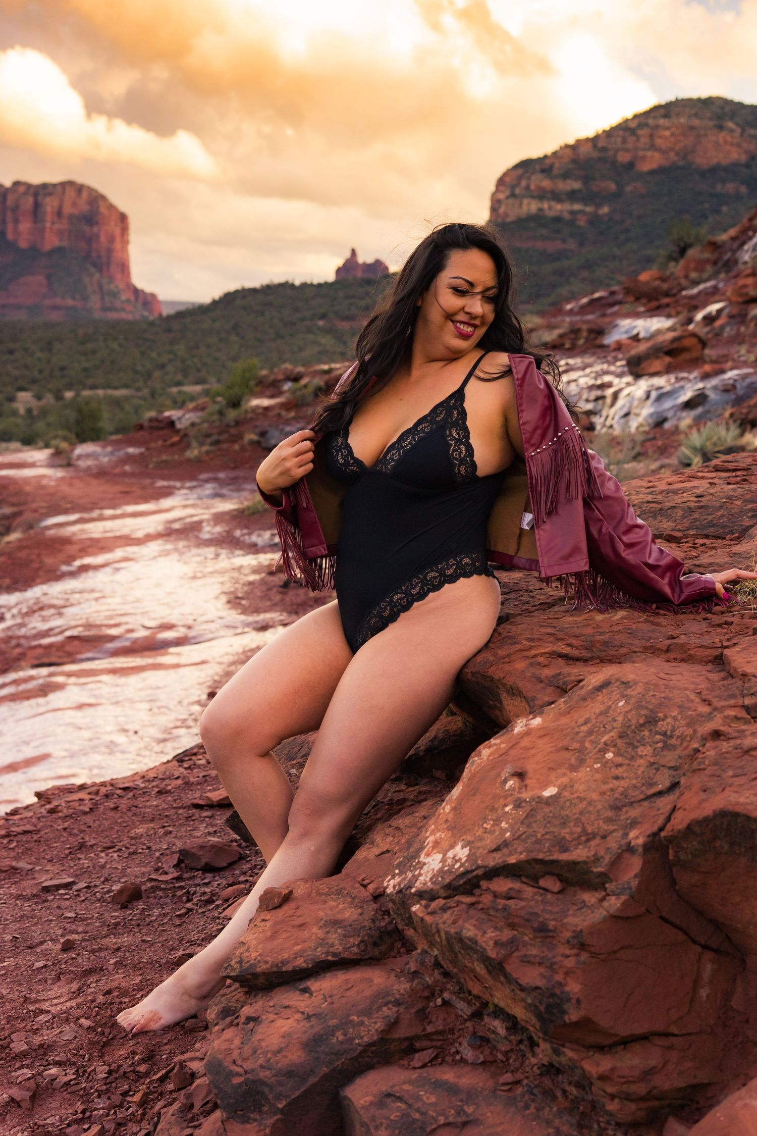 Scenic outdoor portrait in black swimwear with red rock formations and sunset sky.