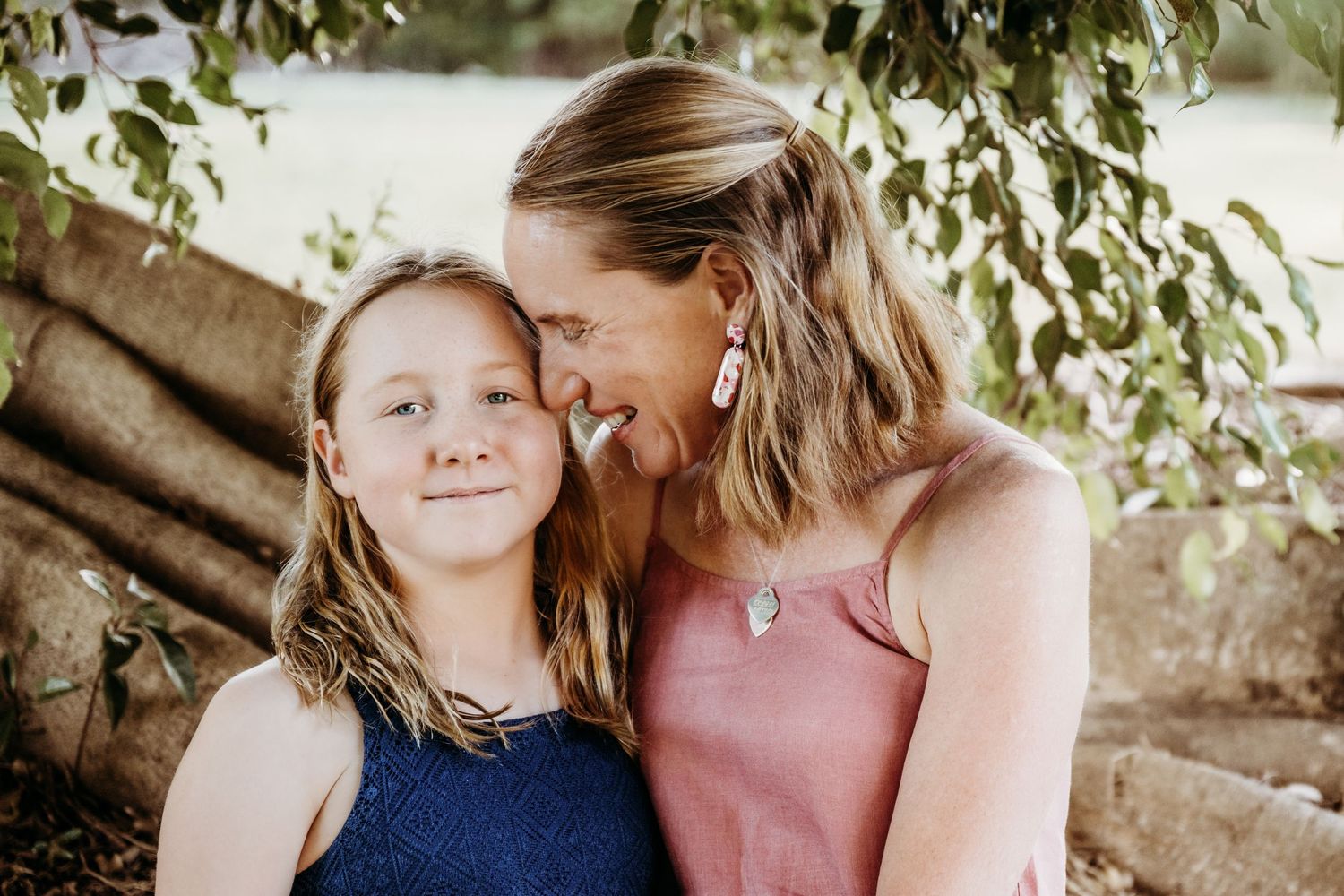 A tender moment shared between two people under tree branches in natural lighting.