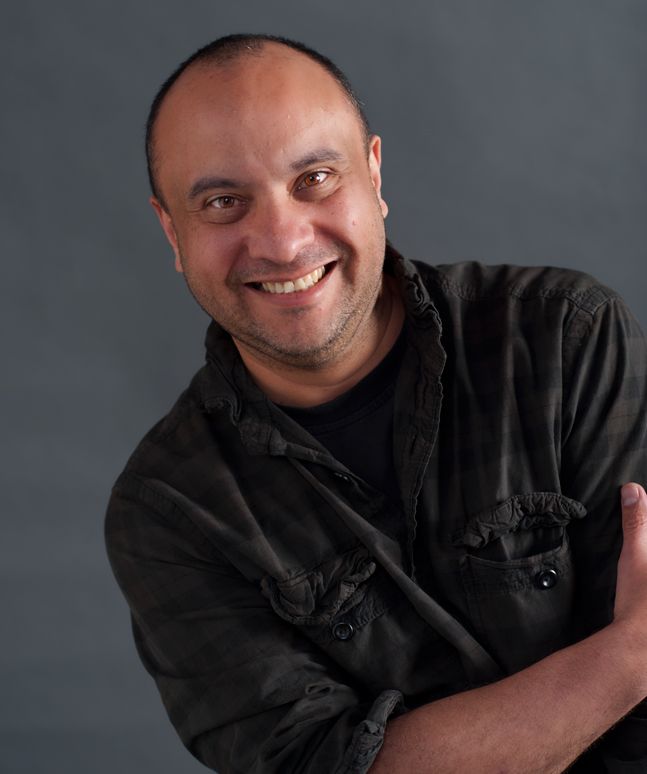 A warm portrait of a person in black clothing against a grey background.