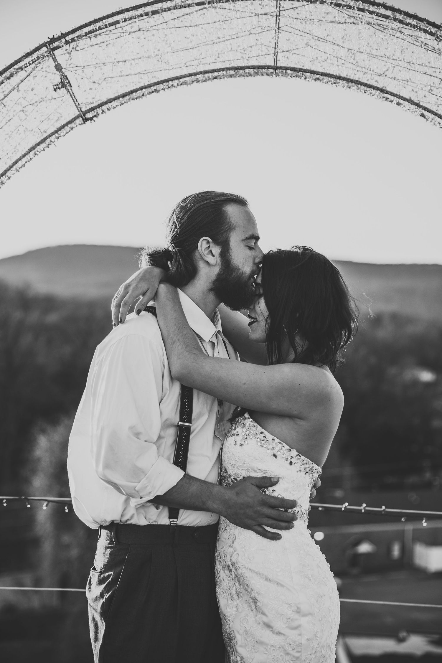 Silhouetted couple sharing romantic moment under archway at sunset.