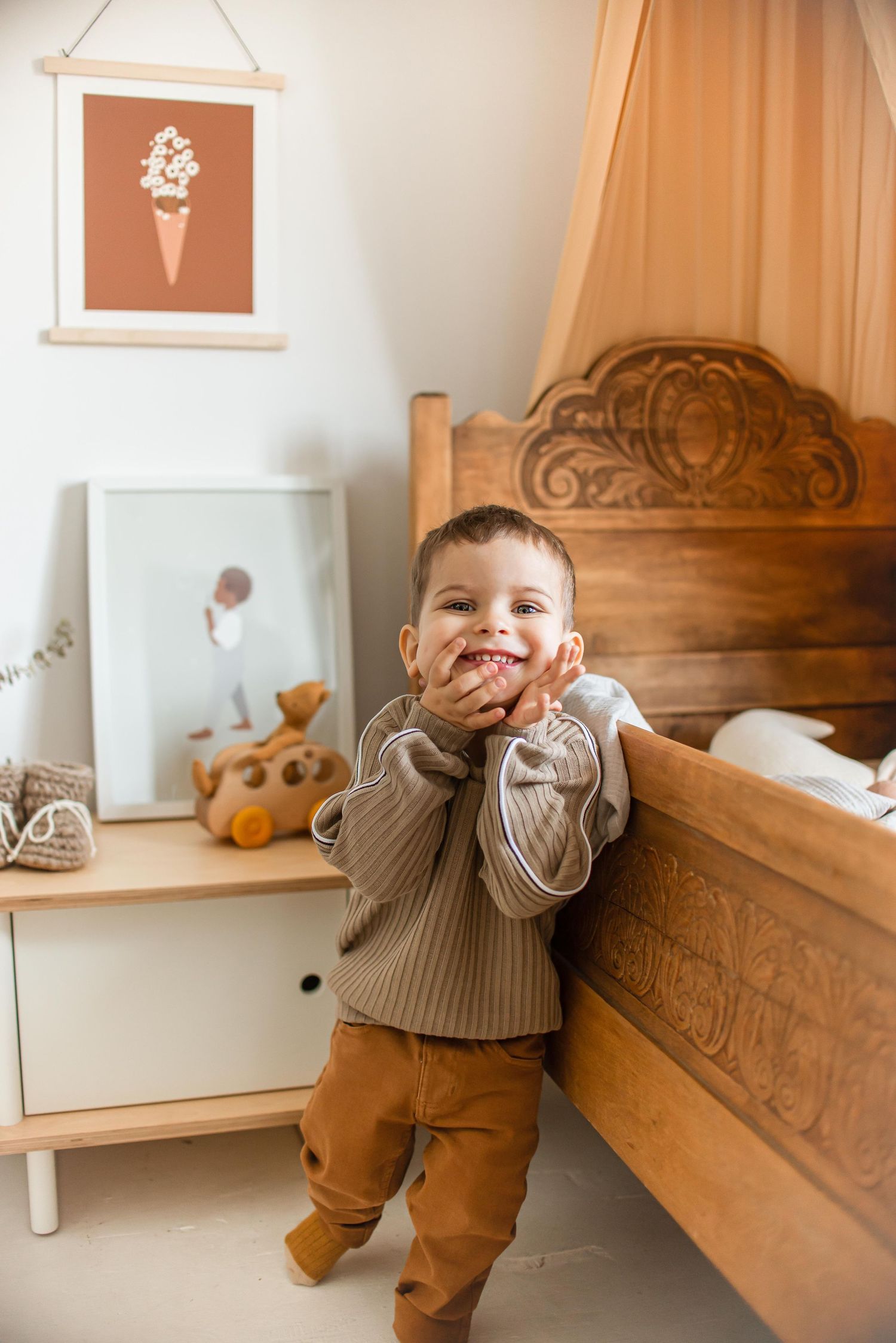 A child's bedroom with wooden bed, ice cream wall art, and neutral decor in warm tones.