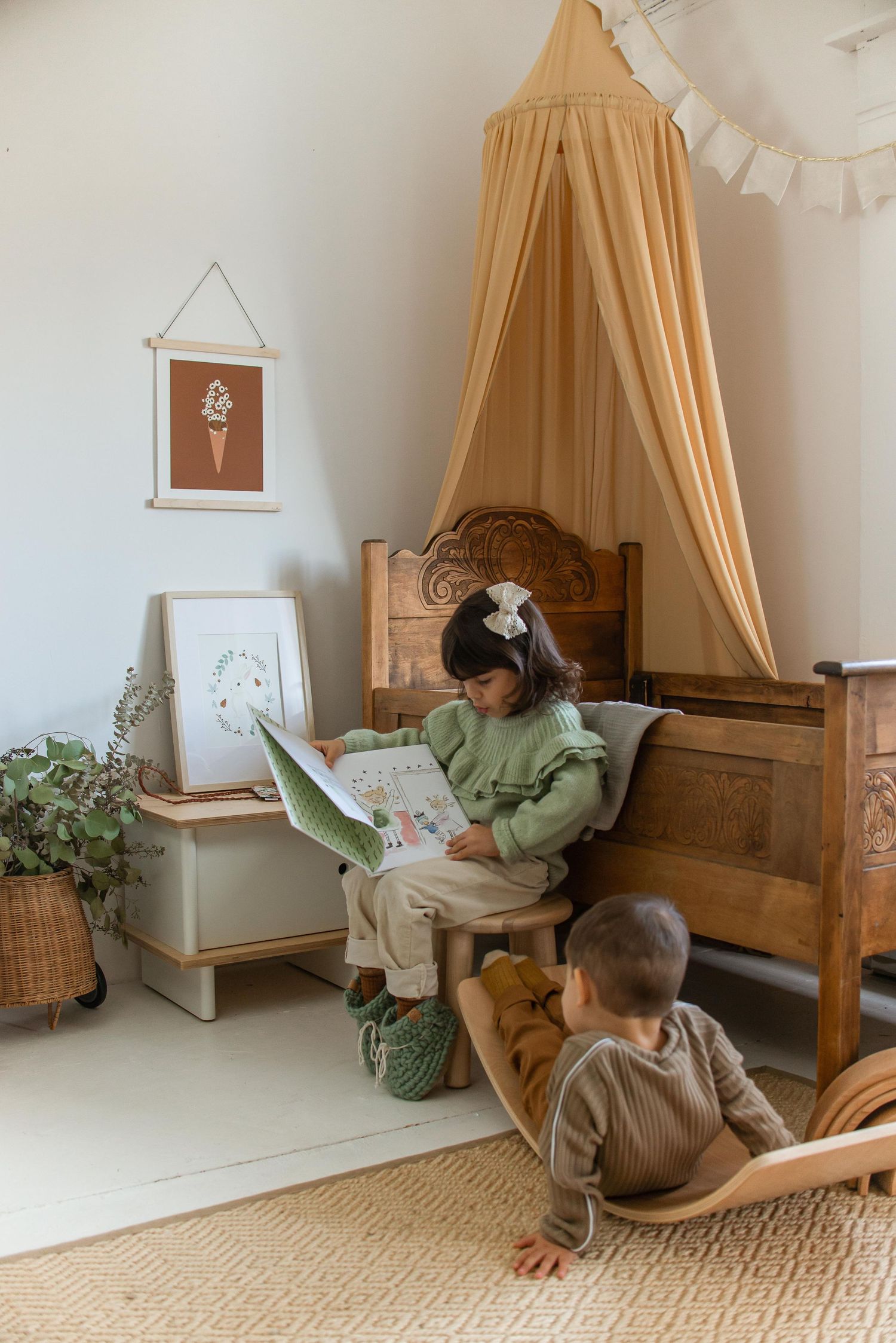 A cozy reading nook with a canopy bed, wooden furniture, and wall art featuring an ice cream illustration.