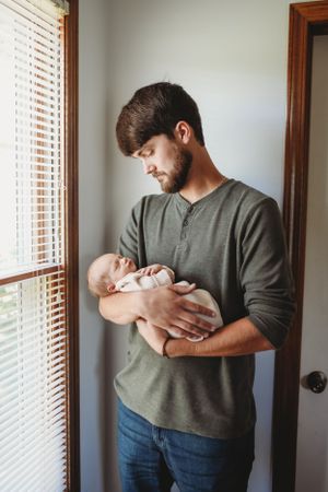 Tender moment captured in minimalist room setting with natural window light.
