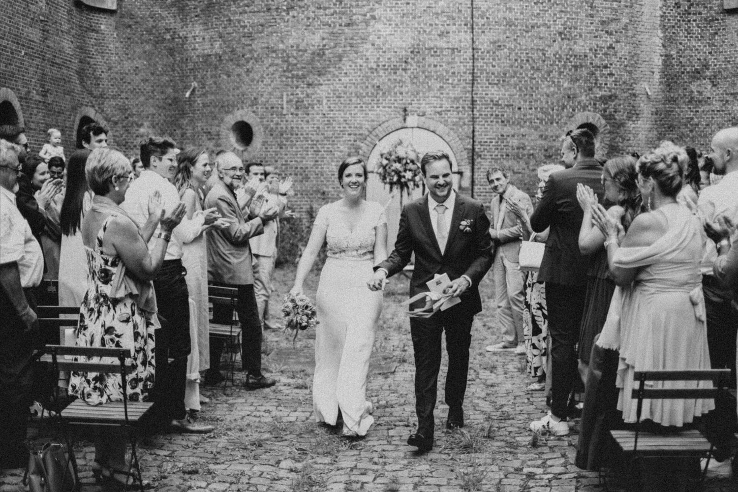 koppel hand in hand einde van de ceremonie tijdens huwelijk in Antwerpen. Het volk applaudisseert