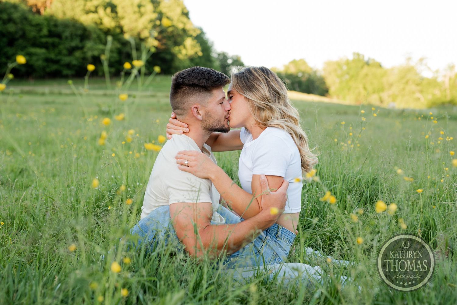 Romantic couple embracing in a sunny meadow filled with yellow wildflowers at sunset.