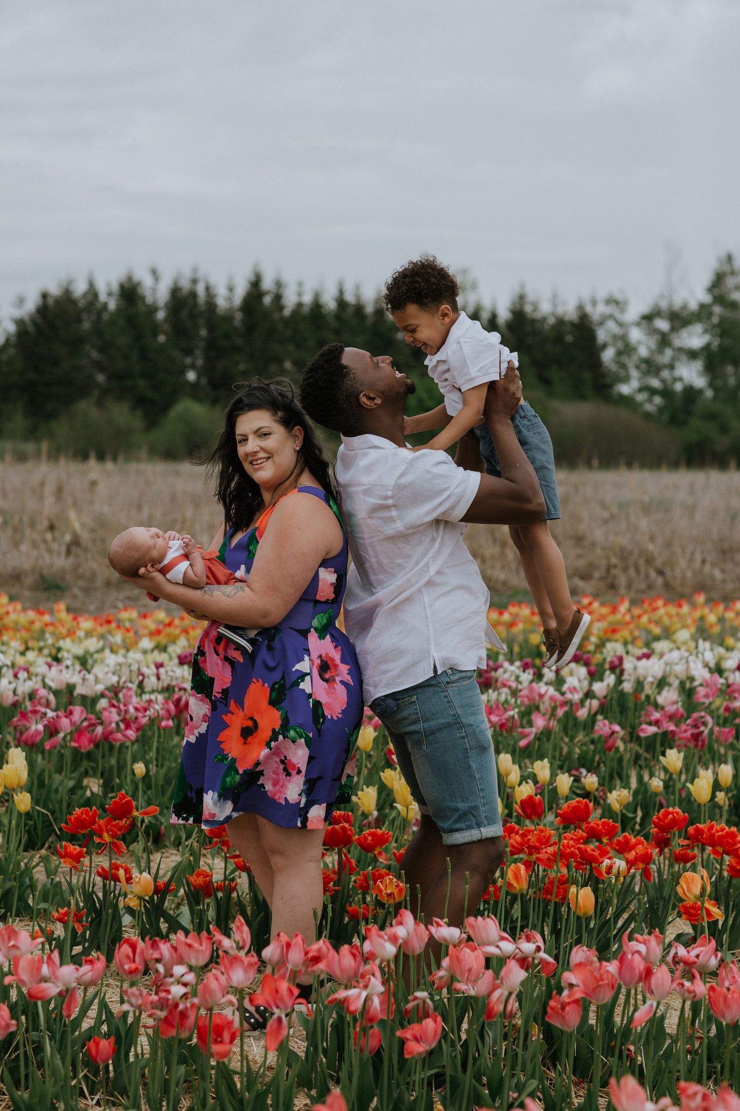 Happy family enjoying a candid moment amidst colorful tulips in a picturesque field near Ottawa, ON.